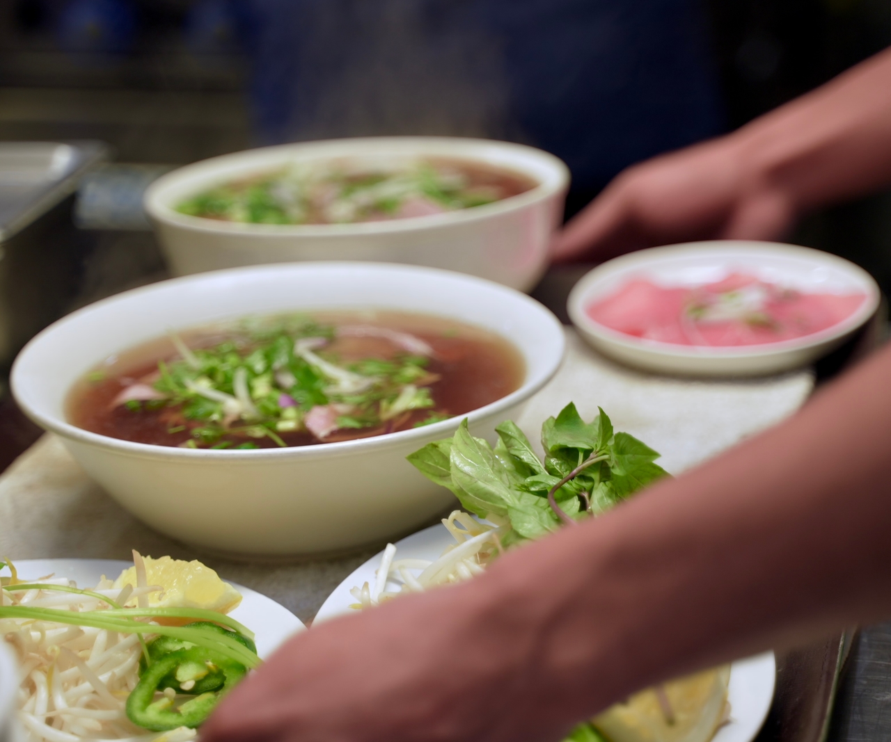 Steaming bowl of Vietnamese Phở with fresh herbs and tender beef